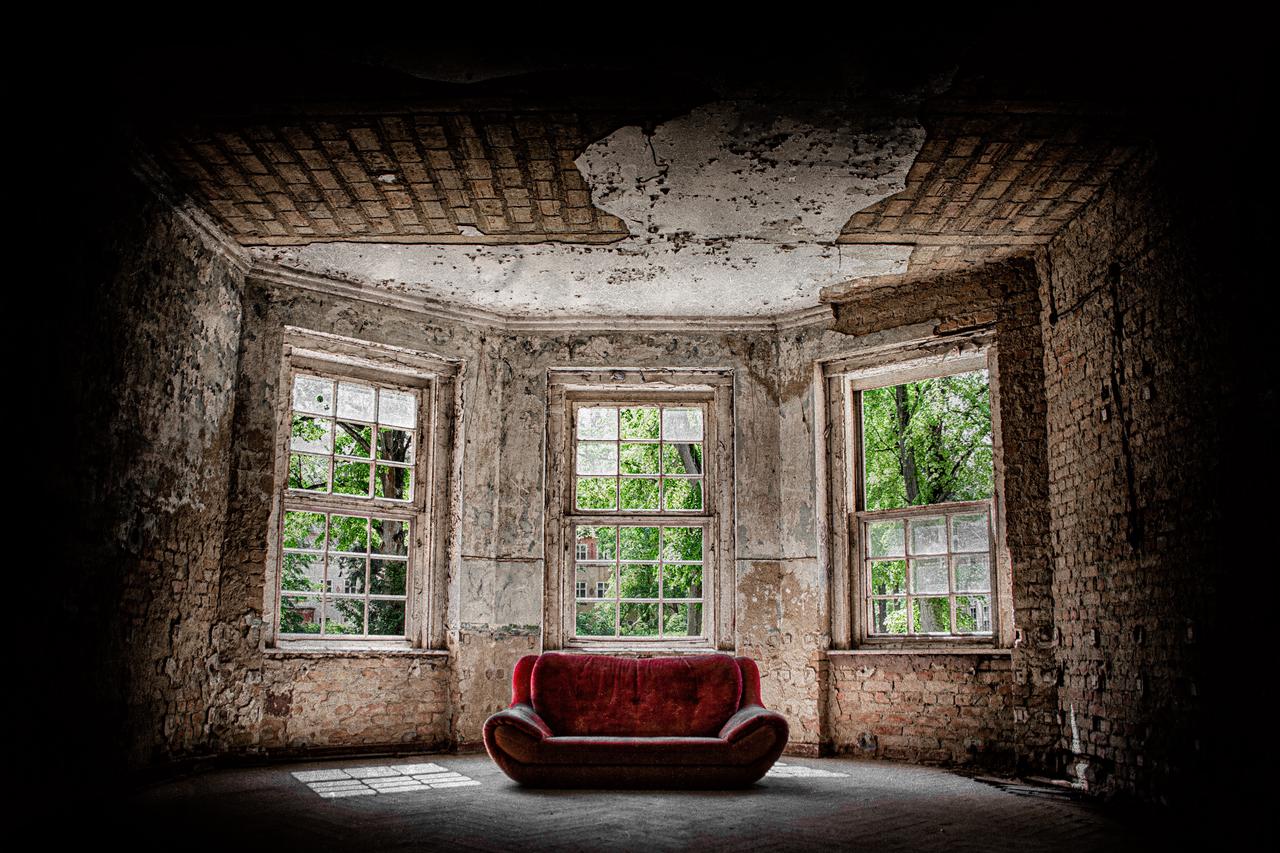 A red sofa in an abandoned house.